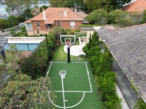 A backyard basketball court with a pool and garden area.