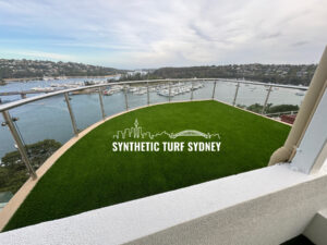 A rooftop with synthetic turf overlooking a harbor and cityscape.