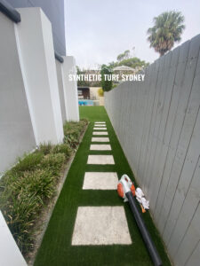 A narrow garden path with stepping stones and a toy gun on the grass.