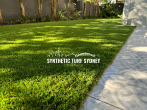 Bright synthetic turf in a sunny backyard with a stone pathway.