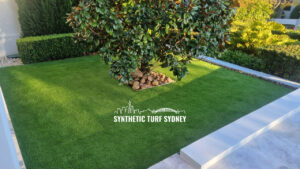 A tree surrounded by synthetic turf and a concrete border in a garden.