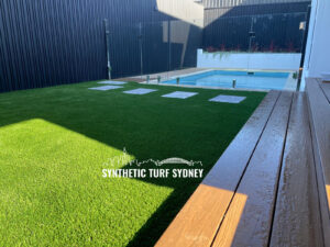 Modern backyard with synthetic turf and a swimming pool under the sun.