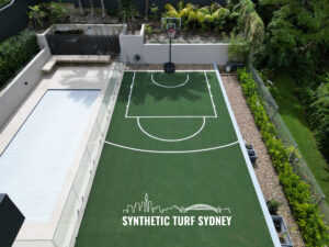 A backyard basketball court with synthetic turf and a small pool.