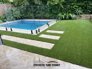 Modern backyard with synthetic turf and a small swimming pool surrounded by greenery.