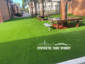 A backyard with vibrant green synthetic turf and wooden benches.