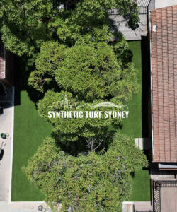 Aerial view of a lush green synthetic turf garden between two buildings.