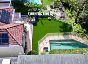A backyard with synthetic turf and a swimming pool beside a house.