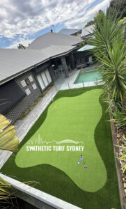 Artificial turf installed in a backyard with a pool and palm tree.