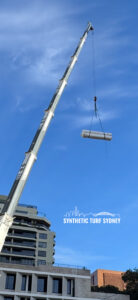 A crane lifting metal pipes against a clear blue sky.