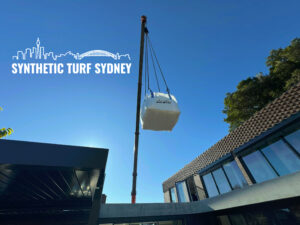 Crane lifting a large object over rooftops under clear blue sky.