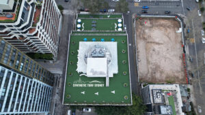 A rooftop sports court with a tennis setup and fitness zone markings.